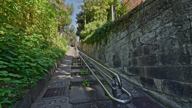 A low-angle view of the steep Munatsuki-zaka stone staircase flanked by greenery and stone walls.