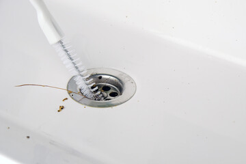 Clearing  clogged sink with  brush, close-up of cleaning the drain hole.