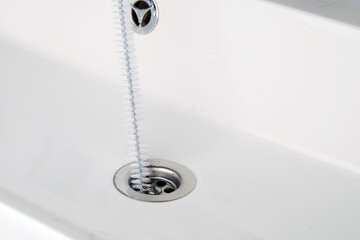 Clearing  clogged sink with brush, close-up of cleaning the drain hole.