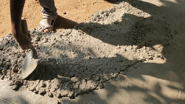 Hands of construction workers smoothing wet cement at a worksite in India, representing labor, infrastructure, civil construction, and real-world working conditions.