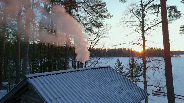 Thick Smoke Billowing from Cabin Chimney during Vibrant Winter Sunset, Traditional Finnish Sauna on a Frozen Lake, Cozy Nordic Lifestyle