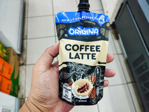 A hand holding a 200ml pouch of Origina Coffee Latte, a ready-to-drink caffeine beverage with a convenient spout.