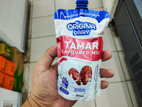 A hand holds a pouch of Origina Dairy Tamar Flavoured Milk, a 200ml date-infused dairy beverage in a store setting.