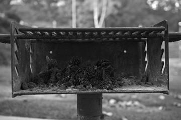 Black and white photo of a public park barbecue grill with ash and charcoal residue in a City of...