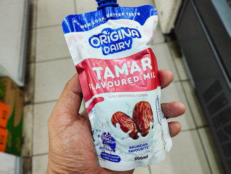 A hand holds a pouch of Origina Dairy Tamar Flavoured Milk, a 200ml date-infused dairy beverage in a store setting.