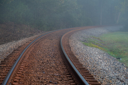 Rural railroad tracks curving into the foggy distance
