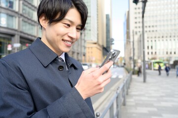 Fototapeta premium オフィス街でスマホを使用する日本人男性
