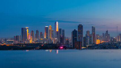 Fototapeta premium Cityscape at Twilight: Modern Skyline with Illuminated Skyscrapers and Reflections in the Water, Urban Landscape at Dusk, Nighttime City View