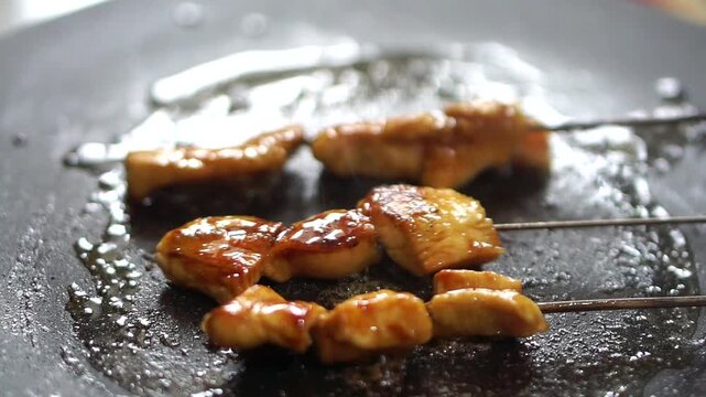 Raw meat satay is skewered and seasoned on a hot griddle to be grilled.