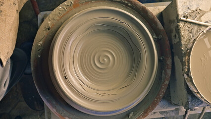 Close-up of a spinning pottery wheel, highlighting the intricate shaping of clay. Smooth, concentric circles showcase the craftsperson's skill and precision.