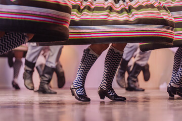Latvian folk dancers in vibrant traditional costumes showcase dynamic movements and rhythmic footwork during a lively cultural performance