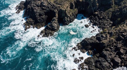 Top-down aerial shot of a rocky seashore, turquoise waves crashing against cliffs, foamy surf