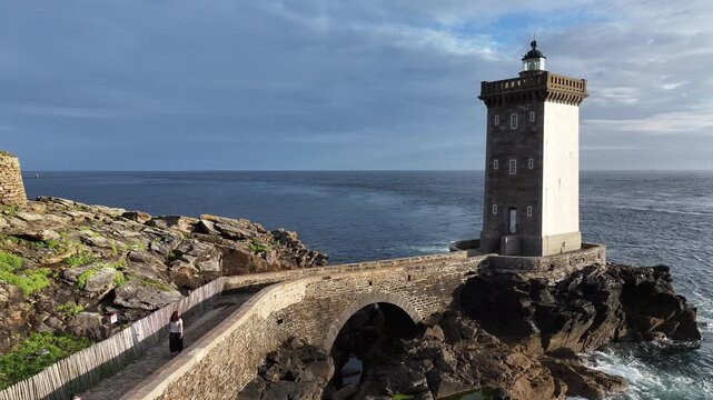 Aerial view of the majestic Phare du Petit Minou lighthouse perched on a rocky outcrop connected by a stone bridge, Bretagne, France.