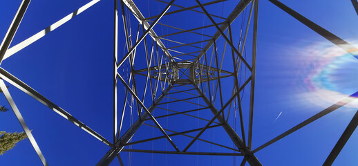 Symmetrical image of a high voltage electrical tower with the sky in the background