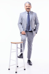 Portrait of confident professional businessman dressed in elegant suit standing against white background