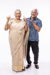 Portrait of happy senior husband holding wife's hands and embracing her while standing against white background.