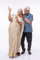 Portrait of happy senior husband holding wife's hands and embracing her while standing against white background.