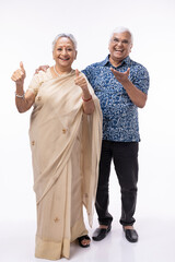 Portrait of happy senior husband embracing wife while standing against white background