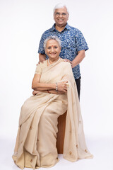 Portrait of happy senior husband embracing wife while standing against white background