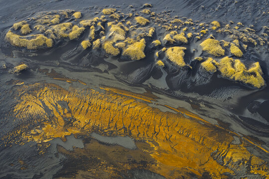 Aerial view of volcanic sands and bright moss creating an abstract painting across Iceland's rugged terrain, Hvolsvollur, Iceland.