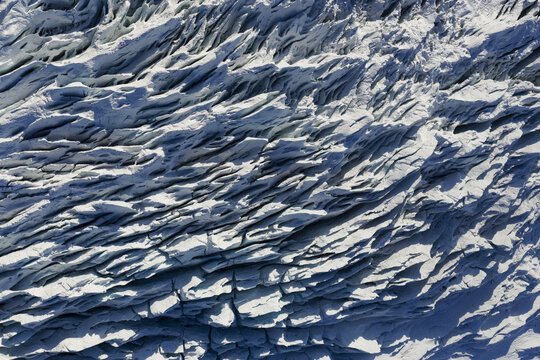 Aerial view of the glacier's icy expanse, a symphony of white and blue contrasting with deep shadows, southern Iceland, Iceland.