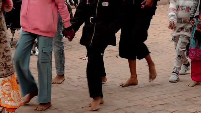 Low angle view of Indian devotees walking barefoot on paved path performing Govardhan Parikrama in winter.