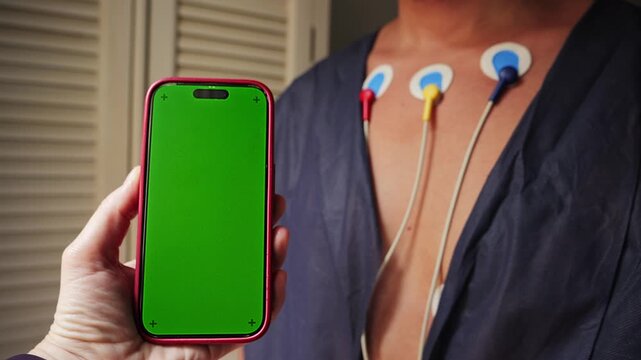 A man wearing a Holter monitor, a portable device that continuously records the heart's electrical activity, A doctor monitors heart activity using a mobile phone app. Chroma key. High quality 4k