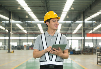 A man wearing a hard hat and safety vest is holding a tablet in his hand. He is smiling and he is enjoying his work