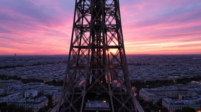 Eiffel Tower's intricate metal structure silhouetted against a breathtaking pink and purple sunset over the Paris cityscape.