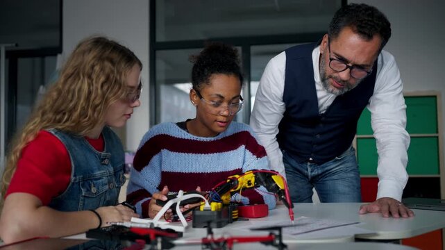 High school students working on robotics project with their teacher.