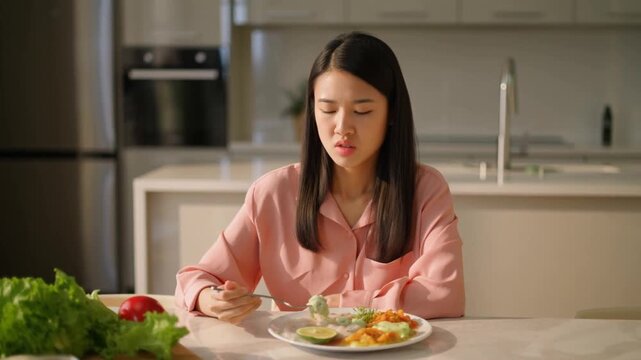 A woman looking displeased while eating a meal. The scene portrays her feeling of eating something she doesn't like Stock Video