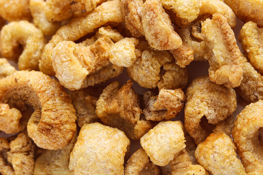 Close-up of crispy, golden-brown fried pork skins. These crunchy, airy pork rinds are a popular savory snack.