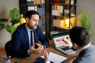 Businessman listening to partner during meeting in modern office