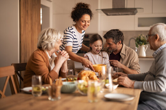 Joyful Family Dinner With Grandparents And Parents Sharing Meal In Modern Home Kitchen