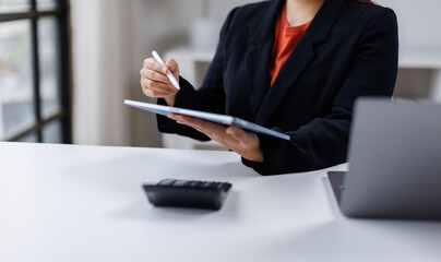 Close-up of hand business woman using a stylus on a digital tablet, working with data and documents at her modern office desk.
