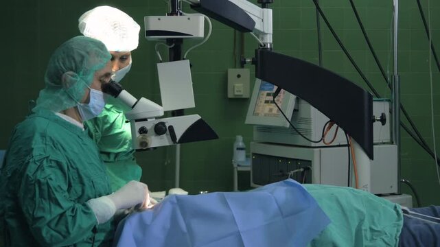 Surgeon and female technician performing cataract surgery on a male patient in a modern high-tech operating room.