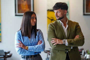 Obraz premium Two people standing with crossed arms in a modern indoor setting during the day