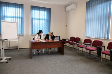 Two women signing documents at desk during business meeting in office