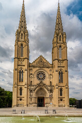 Obraz premium St. Baudile church showcasing its gothic architecture, twin spires, rose window, and fountain