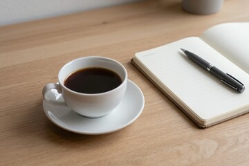 Quiet morning workspace with black coffee and blank notebook ready for notes