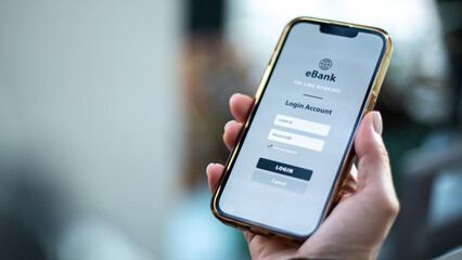 A hand holding a smartphone displaying an eBank login screen with username and password fields.