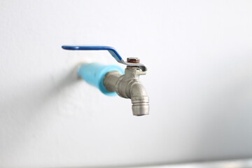  close-up of a water tap (also known as a faucet or spigot) mounted on a white wall.