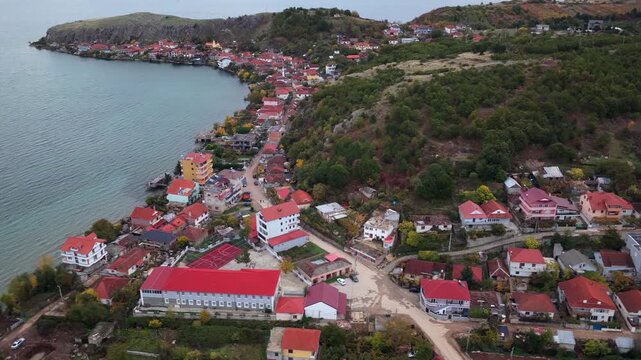 Aerial video of Lin village, its forested hillside, and the calm waters of Lake Ohrid under soft autumn light.