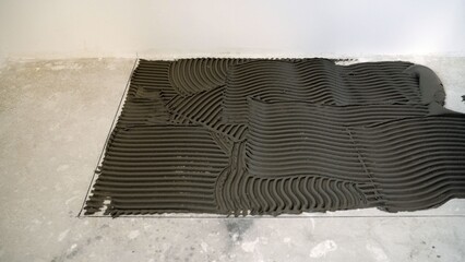 Tile adhesive mortar spread on a concrete floor base, preparing for new flooring installation...