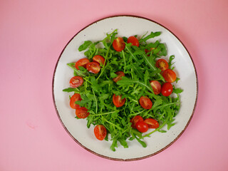 Top view fresh arugula and cherry tomato salad arranged on a plate as a clean healthy step-by-step recipe illustration. Pro photo