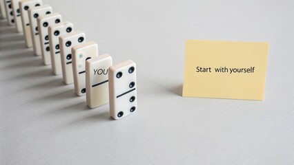 Dominoes standing in a row with start up sticker