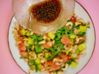 Close up dressing added to salmon shrimp avocado arugula salad showing a clear step by step action in a healthy recipe sequence. pro photo