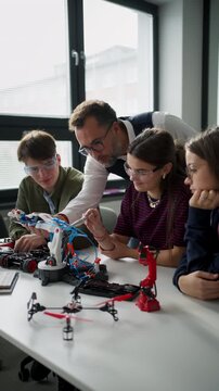 High school students working on robotics project with their teacher.