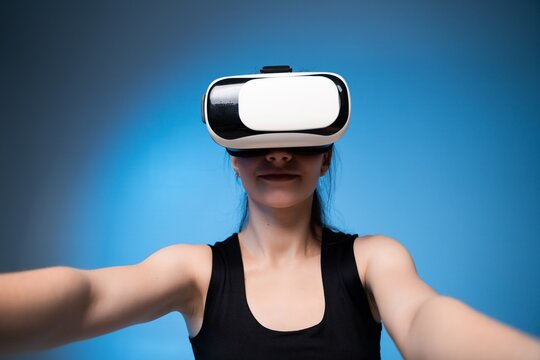 Woman wearing virtual reality headset with arms extended, immersive VR gaming experience, futuristic digital interaction and modern technology concept - Powered by Adobe