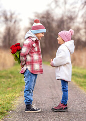 happy boy hidden a bouquet of red roses behind his back as a surprise